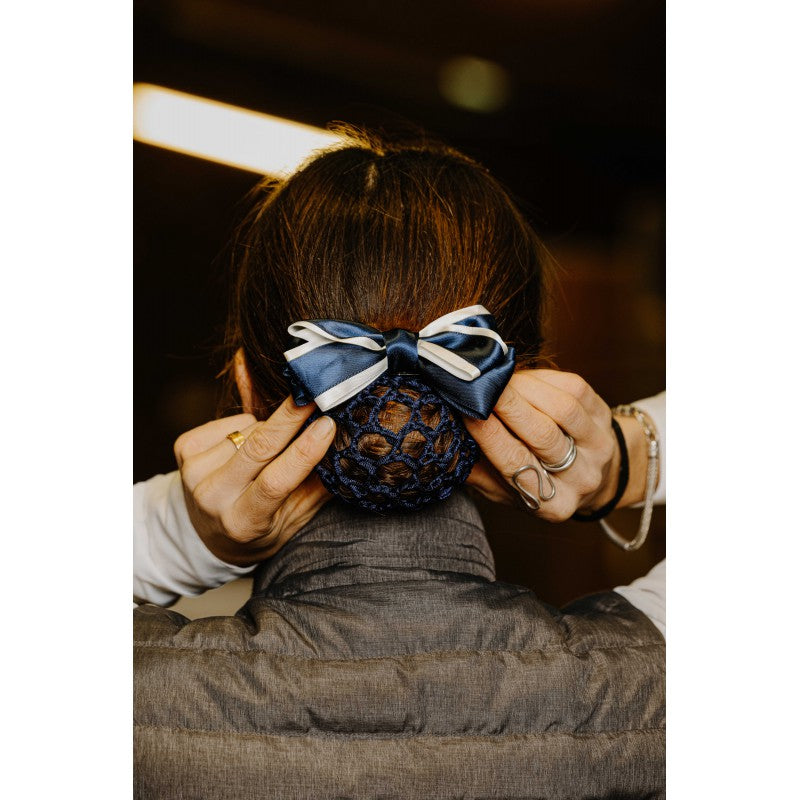 Equitheme Duo navy and white satin bow hair clip worn on a rider's bun in a stable – equestrian competition hair clip at Ekkivibes