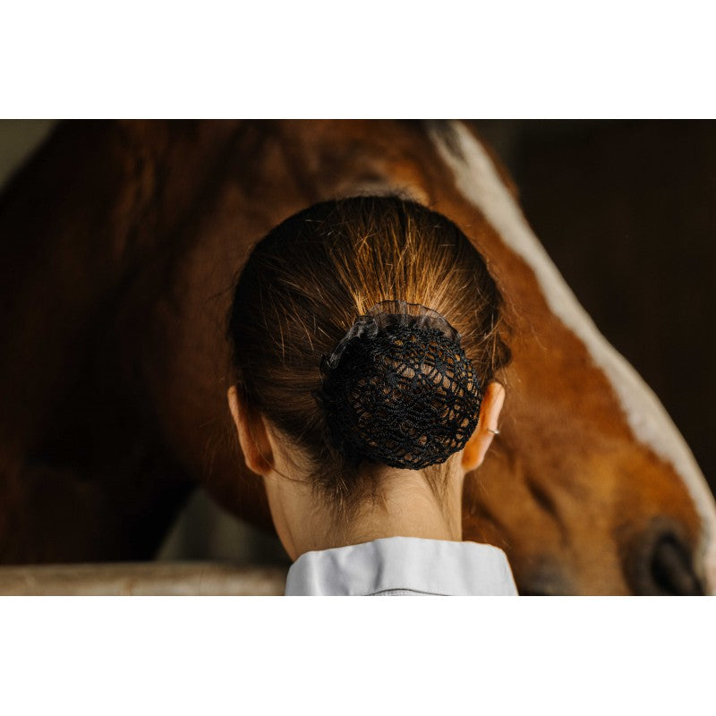 Equitheme Floral black fishnet hairnet worn as a bun by a rider next to a horse – equestrian competition hairnet at Ekkivibes